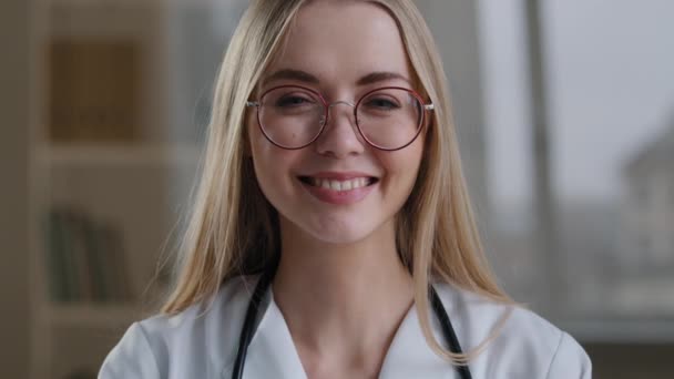 Kaukaski uśmiechnięty szczęśliwy millenium kobieta lekarz w okularach pielęgniarka ortodonta patrząc na aparat stomatologiczny uśmiech pokazując kciuk do góry zaleca szczepienie szczepienia sukces zadowolony dobry znak jak gest — Wideo stockowe