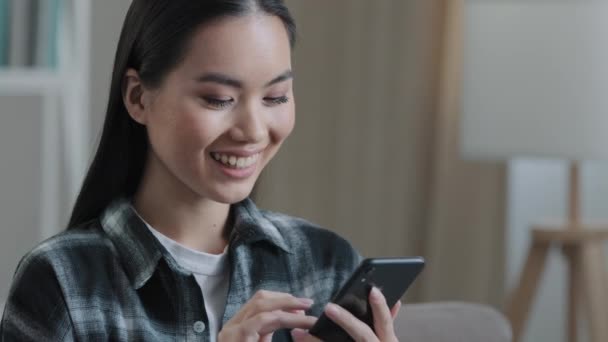 Charkiw, Ukraine - 24.12.2021: Porträt lächelnde asiatische Frau mit Handy-Chat Online-Bestellung Lieferung E-Shopping mit Smartphone-Rabatten in Internet-Shops erhalten Nachricht — Stockvideo
