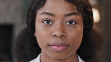 Female portrait indoors alone serious calm confident African American businesswoman intern student girl with perfect skin woman looking at camera in office workspace at home bullying racism feminism
