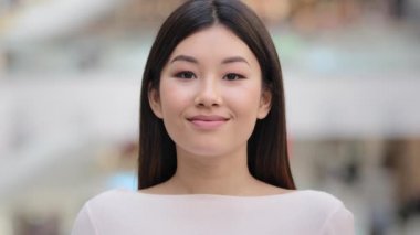 Close up female indoors headshot Asian happy smiling millennial girl. 20s brunette woman model lady with natural make-up face cosmetology service. Businesswoman worker manager client looking at camera