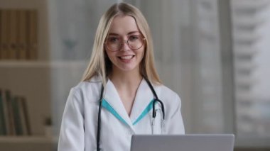 Web kamerası görüntüsü, gözlüklü beyaz kadın hemşire, kapalı klinik hastanesinde oturuyor. Web doktoru kadın, profesyonel terapist tarafından tavsiye ediliyor. İnternet üzerinden uzak teletıp.