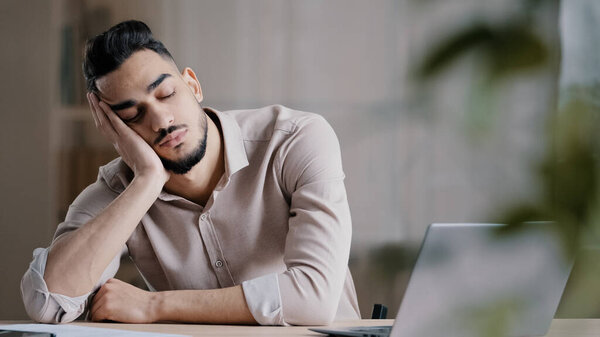 Sleepy tired hispanic man employee male businessman dreamer sleeping at home office workplace napping has rest arabian lazy student overwhelmed unhealthy guy feeling exhausted after hard computer work