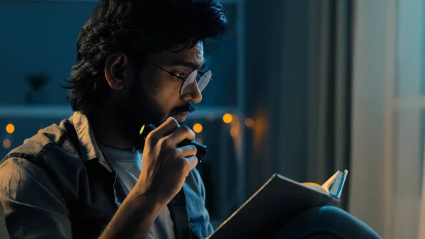 Árabe indio adulto hombre con barba usando gafas sentado en casa noche tarde oscuridad apagón lectura espiritual libro de texto con linterna casa escolaridad estudiar aprendizaje preparación para los exámenes —  Fotos de Stock