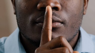 Bilinmeyen gizemli erkek yüzü. Afrikalı Amerikalı yetişkin adam parmağını dudaklarına koydu. Sessiz ol, jest yap, sessiz ol.