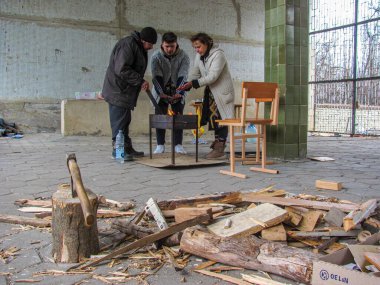 Kharkiv, Ukrayna - 05.28.2022: Çeşit çeşit evsiz erkek kadın soğuk algınlığı olmayan kadın aşçıyı sıcak tut açık havada kal yakacak odun kırma Ukrayna 'daki terör savaşı sırasında hayatta kalma kavramı