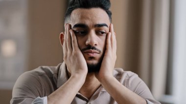 Depresyonda olan İspanyol asıllı erkek işadamı. Evde oturan işadamı. Sıkıntılı bir depresyon, uykusuzluk çeken alnına masaj yapıyor.