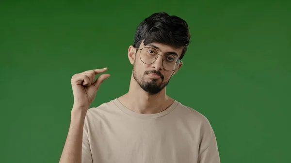 失望的黑发阿拉伯男人用手指做一点手势不满意的男人表现出矮小的身材 矮小的额定尺寸 微小的尺寸 隔离在绿色背景下的室内 — 图库照片