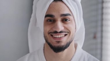 Yüzünde sivilce portresi olan erkek yüzü banyoda duran, banyo havlusuyla gülümseyen, dişlek, Arap, yerli, sakallı bir adam. Beyaz dişli sağlıklı Arap adam kameraya bakıp gülümsüyor.