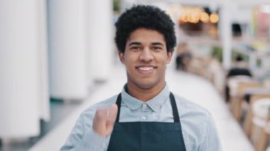Arkadaş canlısı, mutlu, Afro-Amerikalı, önlüklü garson adam. Kafe restoranının küçük işletme sahibi kameraya bakarken mükemmel bir işaret veriyor. Yüksek