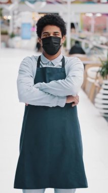 Önlük giymiş dikey görüşlü Afrikalı bir işçi. El ele tutuşup kameraya bakıyor. Amerikan Kafe Müdürü Garson.