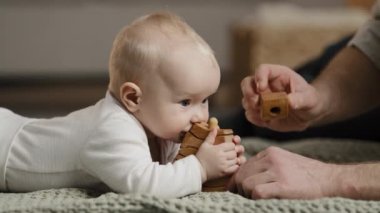 Beyaz bir aile, tanınmayan bir baba, küçük kızıyla, yeni doğmuş bir bebekle evde oyuncaklarla oynaşıyor. Bebek, ahşap bir inşaatçının diş çıkarma kavramını ısırıyor.
