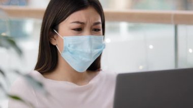 Confused asian woman in medical mask reading bad news about covid19 pandemic receive refuse email on laptop depressed stress unpleasant mistake online lost exam failure dismissal notice job loosing