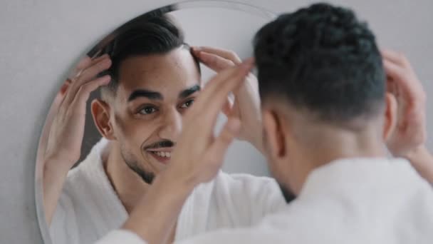 ハンサムな男性モデルインドのヒップスターアラビア髭の男は鏡の反射でヘアスタイルを正しい髪をしています にこにこ30代男性楽しんでアンチふっくらシャンプー結果で朝身づくろいでバスルーム — ストック動画