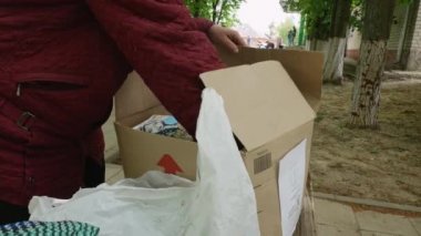 Kharkiv Kharkov bölgesi, Rogan, Ukrayna - 05.10.2022: tanınmayan bir kadın Ukrayna 'daki savaş sırasında ihtiyacı olanlara yardım etmek için gönüllü olarak karton kutuya insani yardım koyuyor