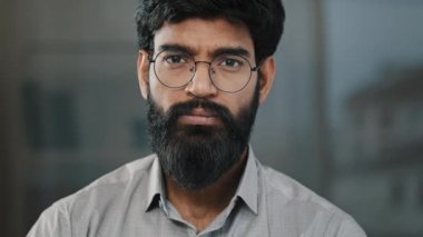 Genç adam, İspanyol yakışıklı sakallı, gülümseyen, kameraya gülümseyen, esmer, Hintli, esmer, iş adamı müdür yardımcısı, kendine güvenen, iyimser bir yüz ifadesi sergiliyor.