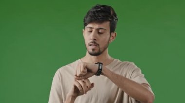 Ciddi sabırsız Arap adamın portresi yeşil arka planda buluşmayı bekliyor. Saate bakıyor. Hayal kırıklığına uğramış İspanyol işadamı.