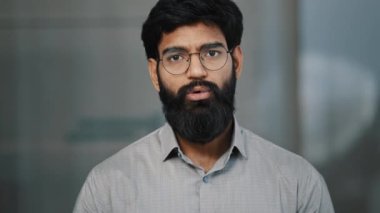 Kendine güvenen genç Arap adamın ön portresi banka çalışanı Hispanik işadamı kapalı bir yerde durup kameraya ciddi bir görüş gözlüğü ile bak sanal görüntülü sohbet hikayesinde bilgi ver