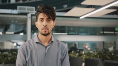 Resmi gömlekli, ciddi Hintli bir iş adamı portresi. İçerde durup profil pozu veriyor. Başını kameraya çevir.