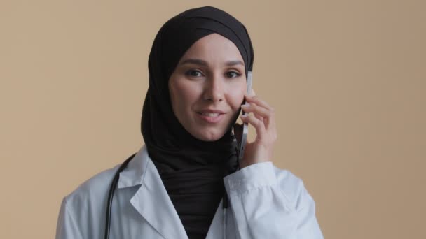 穆斯林伊斯兰医生年轻实习生Arab头戴头巾的女外科医生实习生用手机与病人交谈女顾问咨询远程虚拟移动通信保健概念 — 图库视频影像