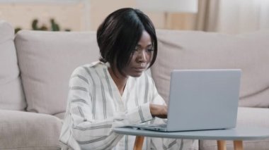 Bilgisayarda yazı yazan, uzaktan kumandalı ev kızı uzaklığı öğrenen, bilgisayar uygulaması kullanan, odaklanmış, Afro-Amerikan kadın serbest yazar sosyal ağda internet mağazasında arama e-postası düzenler.