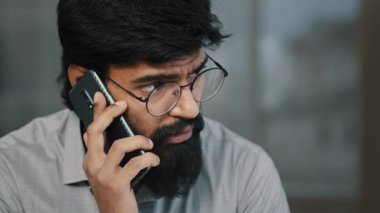 Kendine güvenen yetişkin bir Arap işadamı profesyonel bir işçi kapalı alanda telefonla konuşuyor sakallı adam cep telefonu aygıtı kullanarak uzaktan iletişim projesini tartışıyor.
