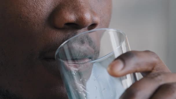 極端なクローズアップ男性の顔アフリカ系アメリカ人の千年の男はさわやかなミネラル液を味わう水の純粋な明確な新鮮な冷たいガラスは 内部的に健康的なルーチン水分を維持渇きに苦しむ — ストック動画