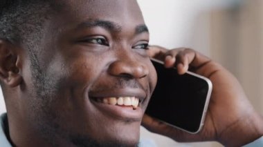 Afrikalı mutlu, kendinden emin erkek işadamı analist müdürü gülümseyen Amerikalı satış elemanı cep telefonuyla konuşuyor müşteri danışma müşterisiyle iletişim kuruyor ev ofisindeki başlangıç projesini tartışıyorlar.