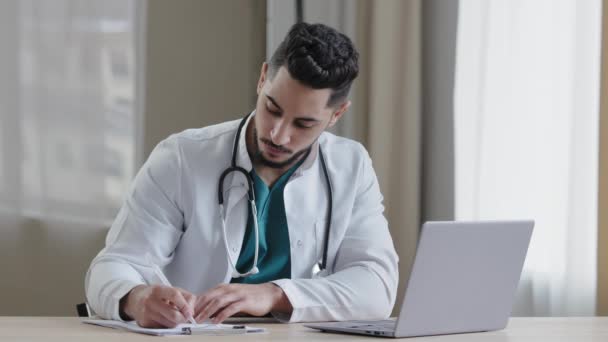 Skoncentrowany Człowiek Arabski Lekarz Lekarz Praktykujący Siedzieć Gabinecie Kliniki Używać — Wideo stockowe