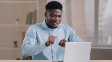 Heyecanlı Afrikalı genç adam. Mutlu Amerikalı iş adamı. Bilgisayarda uzaktan kumandalı çalışan.