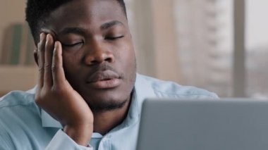 Uykulu, yorgun, Afrikalı erkek ofis erkek hayalperest iş adamı uyku problemi yaşıyor. Masada dinleniyor. Aşırı çalışan tembel, yorgun, yorgun, yorgun, yorgun, bilgisayar başında çalışmaktan yorgun düşmüş.