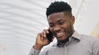 Yakın plan mutlu genç adam telefonda arkadaşlarıyla konuşuyor. Akıllı telefon kullanıyor. Yakışıklı adam kız arkadaşıyla telefonda iletişim kuruyor.
