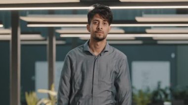 Yakışıklı, bin yıllık Hintli Arap genç adam İspanyol iş adamı, analist, yönetici başını çevirip modern ofiste çapraz kollarla poz veren kameraya bakıyor.