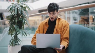 Genç mutlu Hintli adam dizüstü bilgisayar ekranına bakıyor iyi haberleri okuyor internet sayfalarına göz atıyor online mağazada düzenleme yapıyor sosyal ağda iyi fikirlerle iletişim kuruyor davetiyeler alıyor