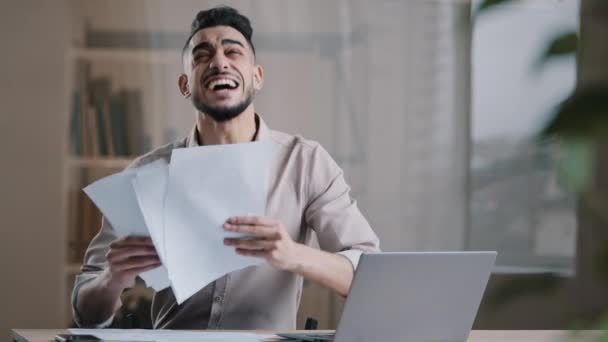 職場で楽しみを持っている幸せな成功した男アラビアのヒスパニック男ビジネスマンは オフィスでの作業日の終わりを祝う空気のダンスで勝利の勝利の投書文書を投げることを喜ぶ完成したプロジェクト — ストック動画