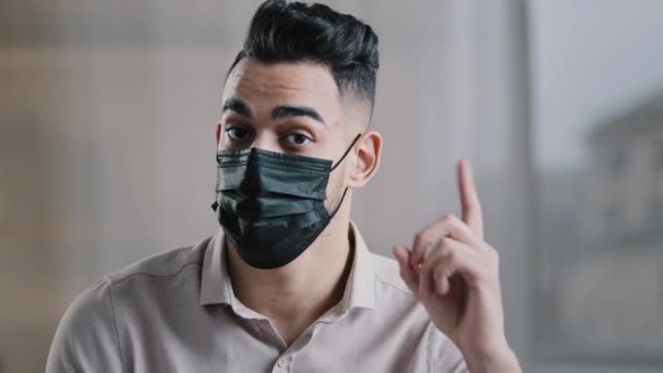ヒスパニック系アラビア人男性労働者実業家男医療マスクで千年男は人差し指の注意信号を上げます発生時に安全距離を維持するために警告ジェスチャーを行いますCovid19否定オファーの意見不一致 — ストック動画