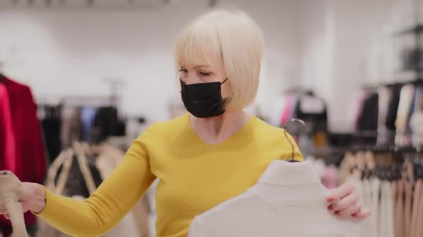Moden Elegant Kvinde Shopper Medicinsk Maske Står Tøjbutikken Vælger Tøj – Stock-video