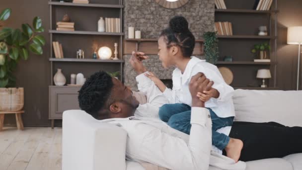 Afrikaanse Vader Liggend Bank Thuis Met Dochter Spelen Figh Game — Stockvideo