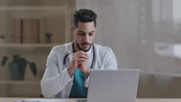 若いアラブのヒスパニック医療セラピスト濃縮医師の専門家の男は コンピュータでホワイトコート使用ヘルスケアサービスアプリを身に着けている患者を相談オンライン専門的な支援遠隔医療の概念 — ストック動画