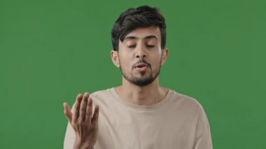 Yeşil stüdyoda tatmin olmamış erkek portresi Hintli sinirli genç adam huzursuz oluyor kayıp jesti agresif hale getiriyor önemli meseleleri açıkla çatışmalar negatif tutumlar