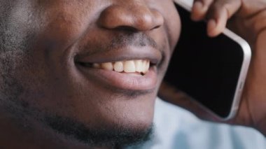 Tanımlanamayan erkek yüzünü kapat Afrikalı Amerikalı genç adam cep telefonuyla konuş iletişim mesafesi konsültasyonu yap müşteri ev ofisinden iyi haber telsizini paylaş