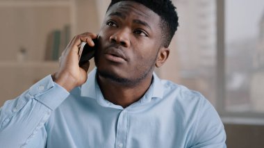 Afrikalı iş adamı Amerikalı erkek işçi ev telefonundan gelen çağrıya cevap veriyor hayal kırıklığına uğramış genç adam kötü haber alış verişi olumsuz bilgi alıyor.