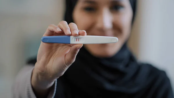Portrait smiling blurred arabian young woman pregnant muslim girl in hijab future mother showing positive pregnancy test result on camera sharing good news in anticipation of childbirth maternity love