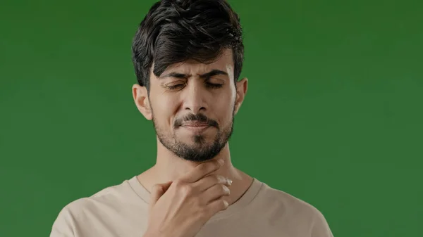 インドの病気の若いアラブ人の男性のタッチ首は狭心症に苦しむ喉の痛み不健康な男痛みを伴う飲み込む感じ不快感コロナウイルス病症状呼吸器感染は緑のスタジオで隔離スタンド — ストック写真