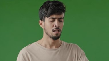Hasta, alerjik Arap erkek, Hintli, kötü adam, yüz yüze hapşırıyor, yeşil stüdyo arka planında yayılan viral enfeksiyonu önlüyor, soğuk algınlığı belirtileri var, solunum alerjisi, burun silme.