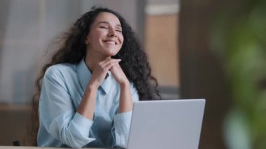 Tasasız, güzel genç kadın, iş yerinde mola verdi. İspanyol iş kadını, kıvırcık saç stili, temiz hava üfleyen, rahatlatıcı dans hareketleri yapan, klimadan serinlik esintisi hisseden kadın.