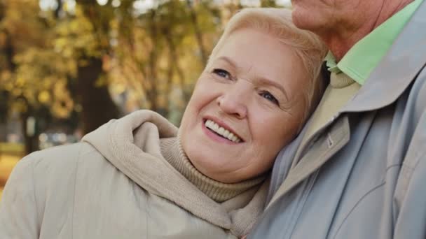快乐的中年漂亮的高加索老妇人微笑着站在秋天的公园里放松地待在户外靠在肩膀上成熟的伴侣男人支持丈夫表现出移情关怀爱情浪漫 — 图库视频影像