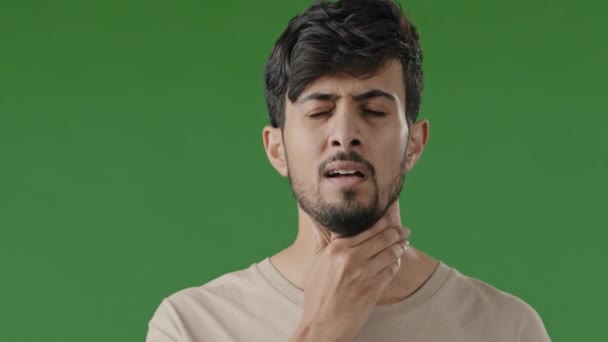 インドの病気の若いアラブ人の男性のタッチ首は狭心症に苦しむ喉の痛み不健康な男痛みを伴う飲み込む感じ不快感コロナウイルス病症状呼吸器感染は緑のスタジオで隔離スタンド — ストック動画
