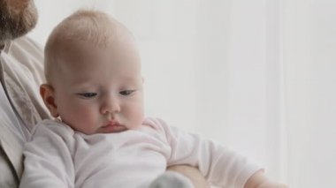 Küçük beyaz, sevimli, komik, yeni doğmuş bir kız çocuğu ve tanınmayan bir babası var. Ayaklarından tutarak oynayan çocuk. Bebek çorapları. Evde oynayan çocuk çorapları.