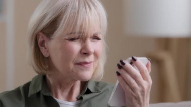 Yakın plan yaşlı kadın, yetişkin kadın, beyaz kadın, telefon ekranına bakan emekli kadın. Görme bozukluğu, kötü görme bozukluğu, gözlerde hasar, gözlük ya da lazer düzeltmesi.