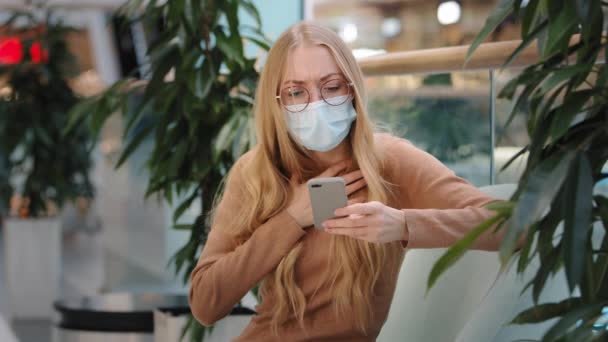 Mujer Caucásica Rubia Descontenta Máscara Médica Mirando Pantalla Del Teléfono — Vídeo de stock